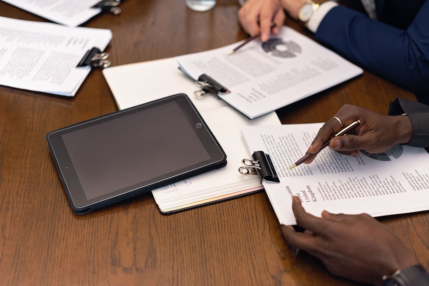 People review documents and a tablet at a table.