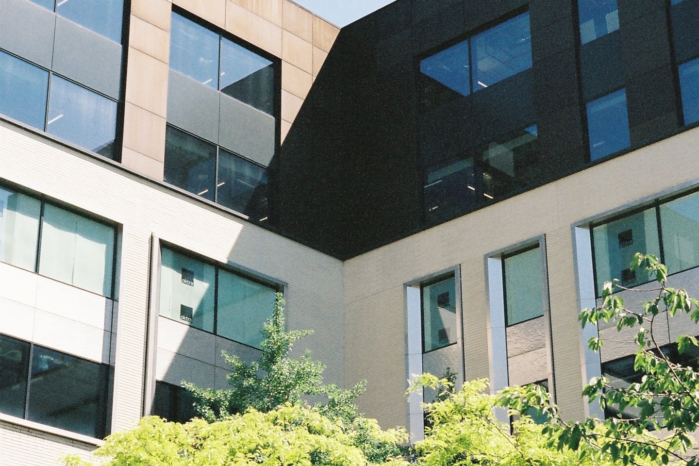 A modern office building is surrounded by mature greenery.