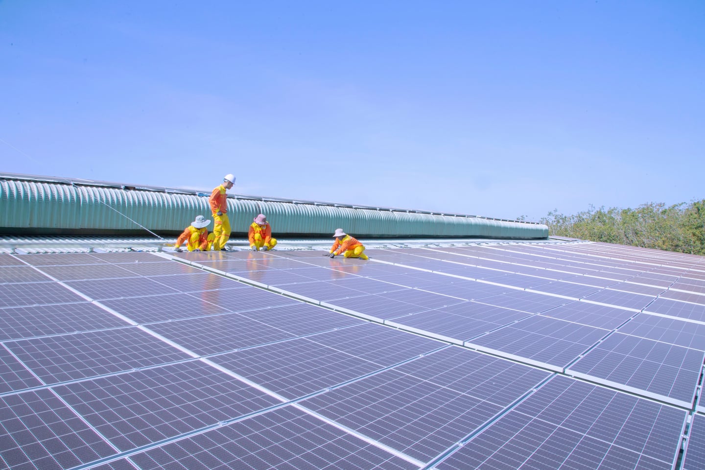 A team installs solar panels on a large roof.