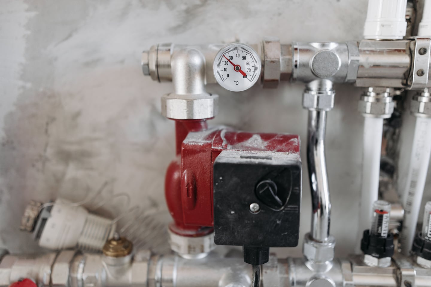 Industrial pipes and a pressure gauge run along a utility wall.